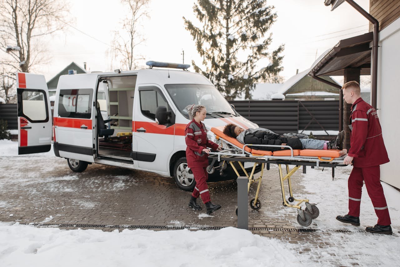 Paramedics transporting a patient on a stretcher to an ambulance on a snowy day.